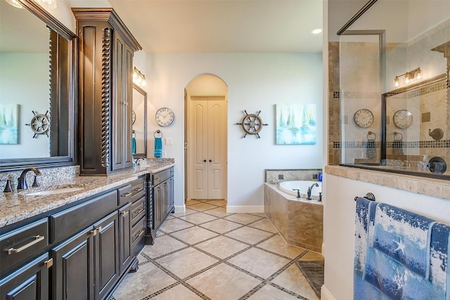 full bath with a garden tub, a sink, baseboards, a tile shower, and double vanity