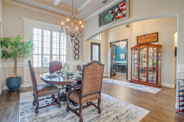 dining space with wood finished floors, visible vents, arched walkways, crown molding, and a notable chandelier