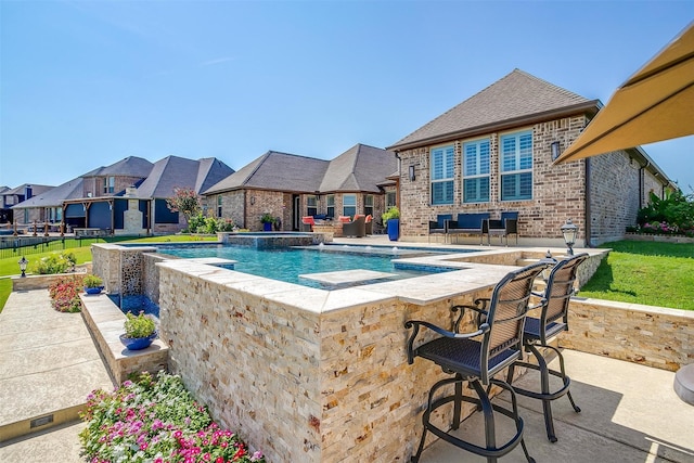 view of swimming pool featuring a bar, a pool with connected hot tub, a residential view, and a patio