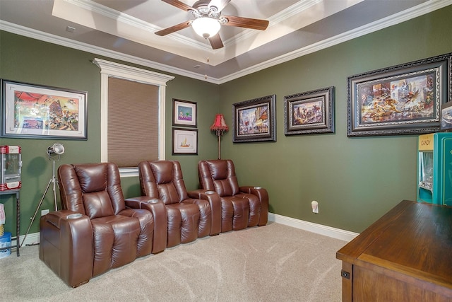 carpeted cinema room featuring ceiling fan, a raised ceiling, baseboards, and ornamental molding