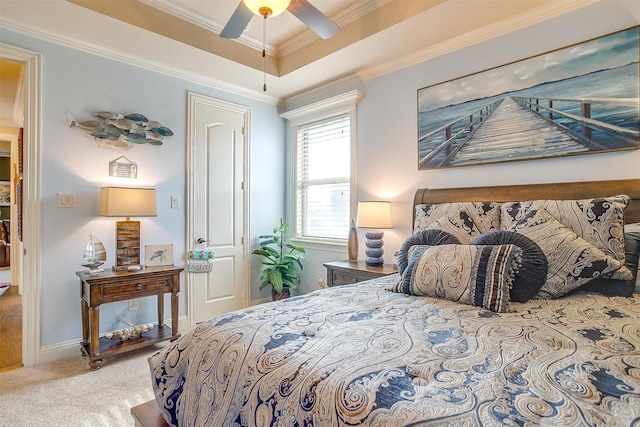 carpeted bedroom featuring ceiling fan, a tray ceiling, baseboards, and ornamental molding