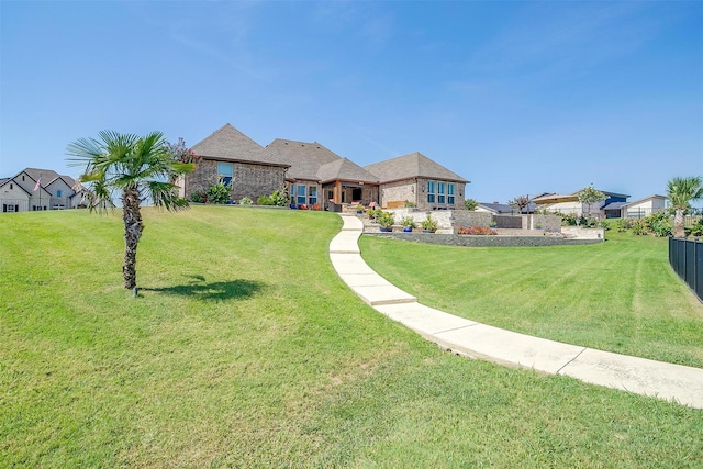 view of front of property with brick siding, a front yard, and fence