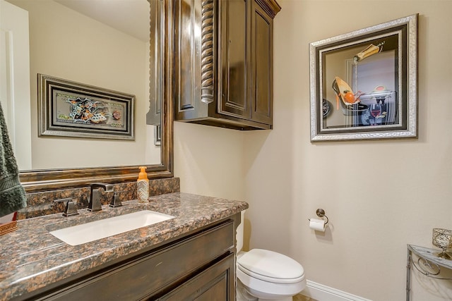 bathroom featuring toilet, vanity, and baseboards