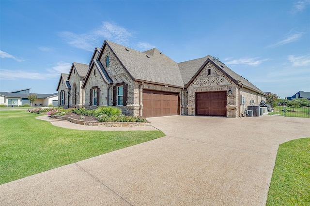 french country home with a garage, brick siding, fence, stone siding, and a front yard