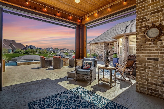 patio terrace at dusk with outdoor lounge area, an in ground hot tub, an outdoor pool, and a residential view