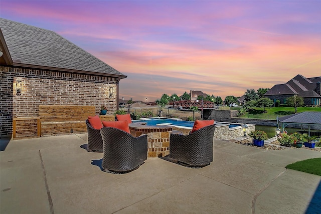 pool at dusk featuring a patio area, fence, and a pool with connected hot tub