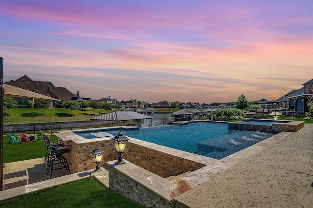 pool at dusk featuring outdoor dry bar, a pool with connected hot tub, a patio, fence, and a gazebo