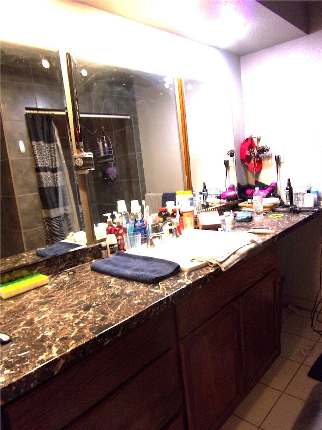 bathroom featuring tiled shower, vanity, and tile patterned flooring