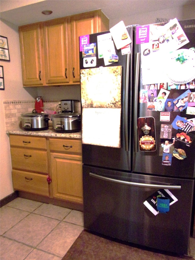 kitchen featuring light tile patterned floors and black fridge