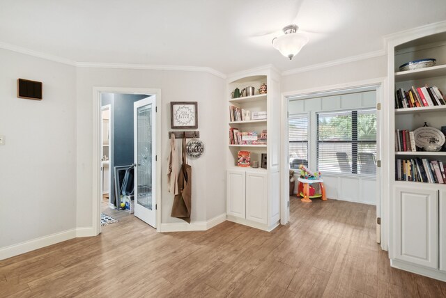 misc room with built in shelves, light wood-type flooring, and crown molding