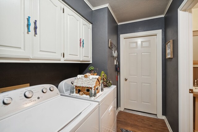 washroom with a textured ceiling, hardwood / wood-style floors, cabinets, washing machine and clothes dryer, and ornamental molding