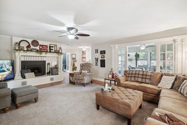 living room featuring decorative columns, a fireplace, ornamental molding, ceiling fan, and hardwood / wood-style floors