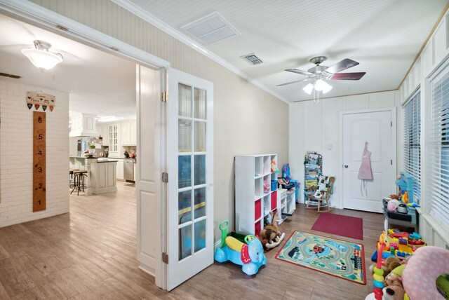 game room featuring light hardwood / wood-style flooring, crown molding, and ceiling fan