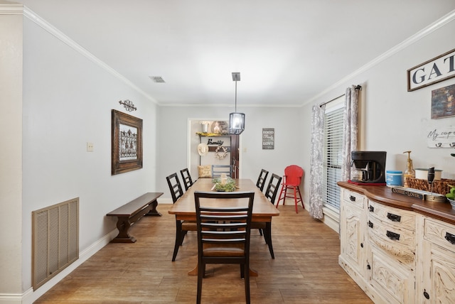 dining area featuring a notable chandelier, crown molding, and light wood-type flooring