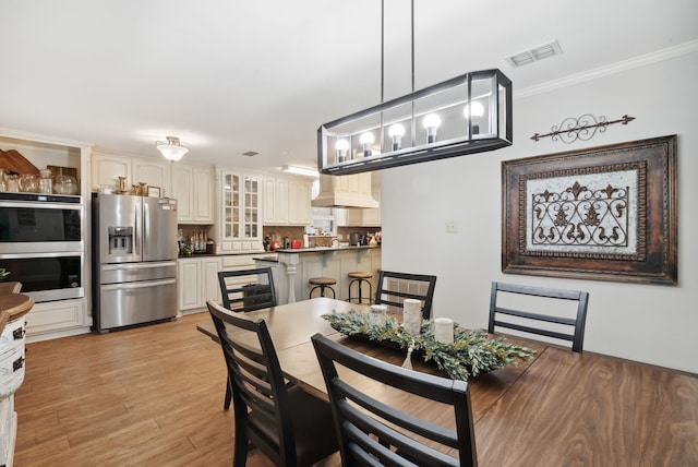 dining area featuring light hardwood / wood-style flooring and crown molding