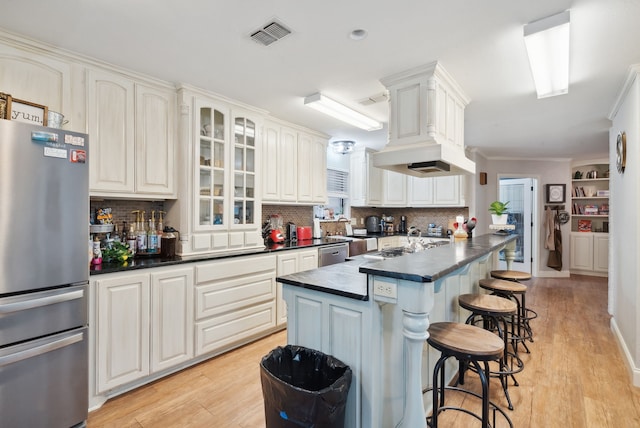 kitchen featuring light wood-type flooring, a breakfast bar area, stainless steel appliances, decorative backsplash, and a kitchen island