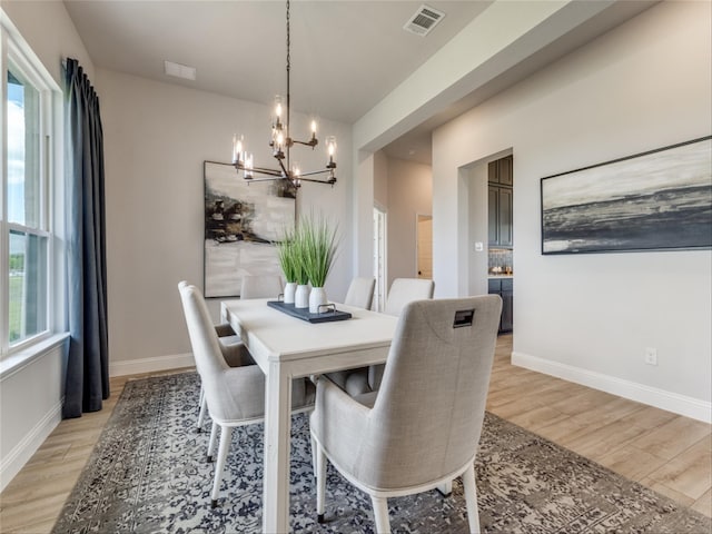 dining area with light hardwood / wood-style flooring, a notable chandelier, and plenty of natural light