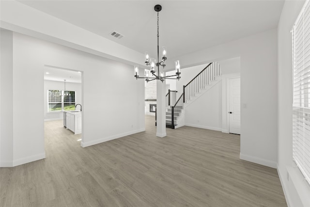 unfurnished dining area with light hardwood / wood-style floors, an inviting chandelier, and sink