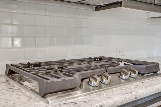 interior details with stainless steel gas stovetop, backsplash, and light stone counters