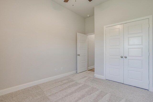 unfurnished bedroom featuring a closet, light colored carpet, and ceiling fan