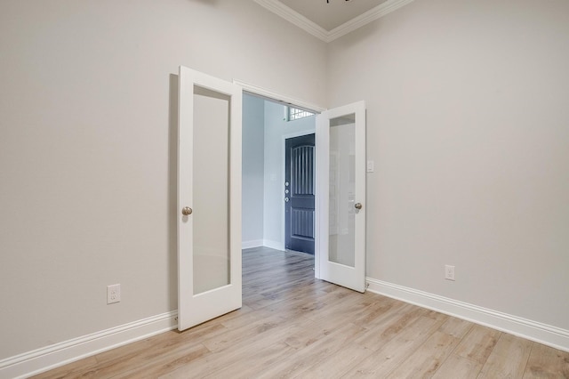 empty room featuring light wood-type flooring, ornamental molding, and french doors