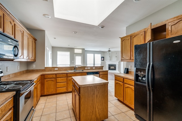 kitchen featuring light tile patterned floors, black appliances, kitchen peninsula, a center island, and sink