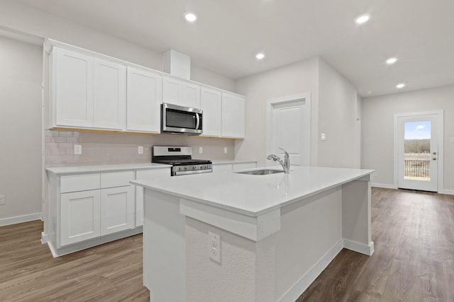 kitchen with stainless steel appliances, sink, a kitchen island with sink, and white cabinets