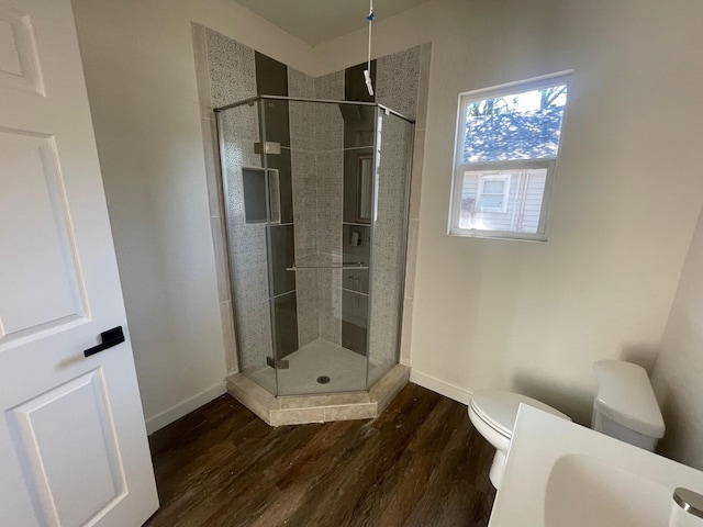 bathroom with hardwood / wood-style flooring, an enclosed shower, and toilet