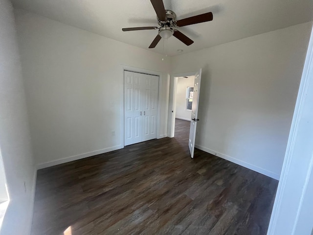 unfurnished bedroom with ceiling fan, dark wood-type flooring, and a closet