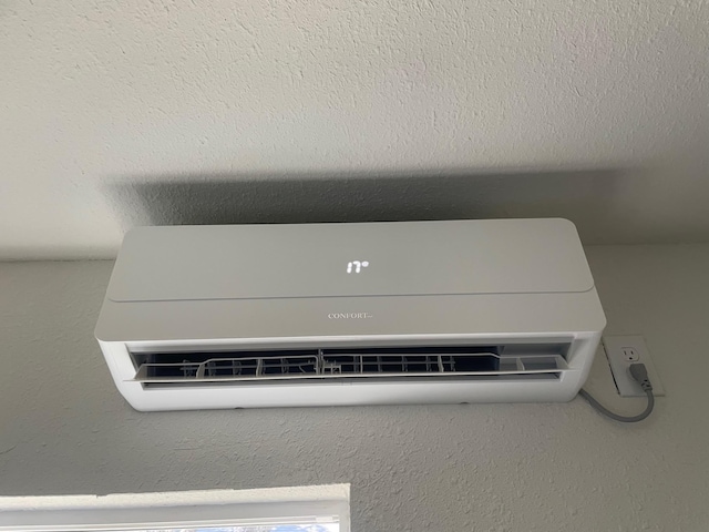 room details featuring a textured ceiling and a wall unit AC