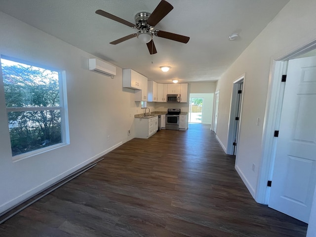 unfurnished living room with ceiling fan, sink, dark hardwood / wood-style flooring, and a wall mounted AC