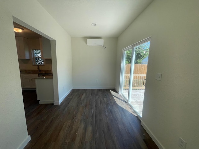 unfurnished dining area with sink, dark wood-type flooring, and a wall mounted air conditioner