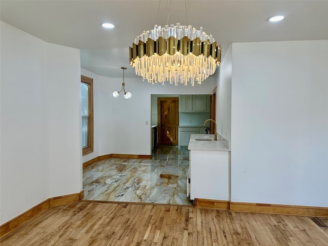 empty room featuring sink, light wood-type flooring, and a chandelier