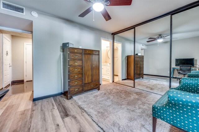 bedroom featuring ceiling fan, ensuite bath, a closet, and light hardwood / wood-style floors