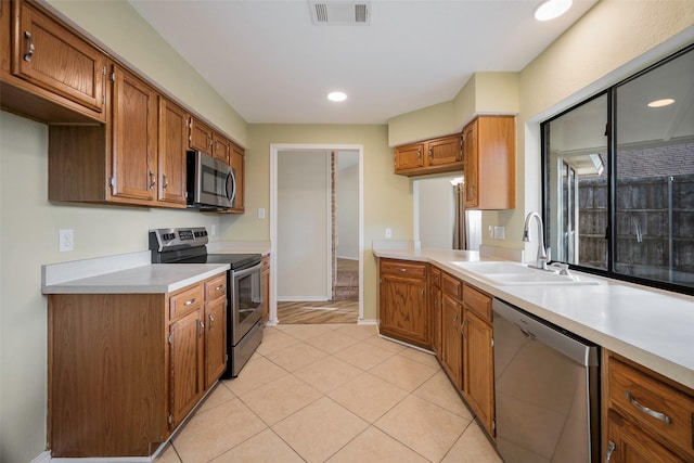 kitchen featuring appliances with stainless steel finishes, light tile patterned floors, and sink