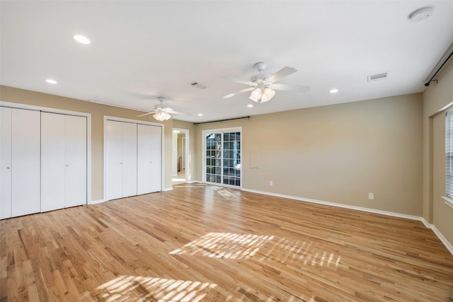 unfurnished bedroom with ceiling fan, light hardwood / wood-style flooring, and two closets