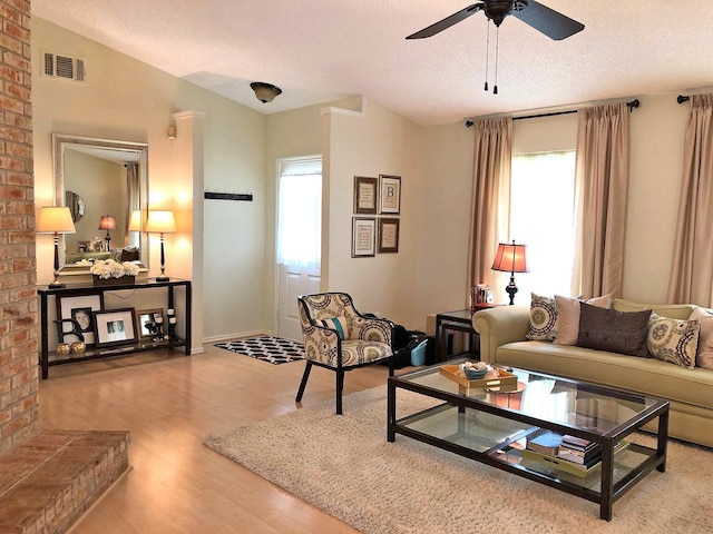 living room with a wealth of natural light, hardwood / wood-style floors, ceiling fan, and a textured ceiling