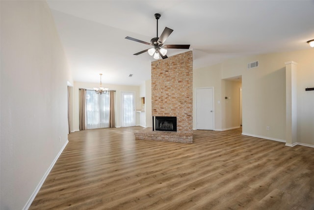 unfurnished living room featuring a brick fireplace, ceiling fan with notable chandelier, dark hardwood / wood-style flooring, and vaulted ceiling