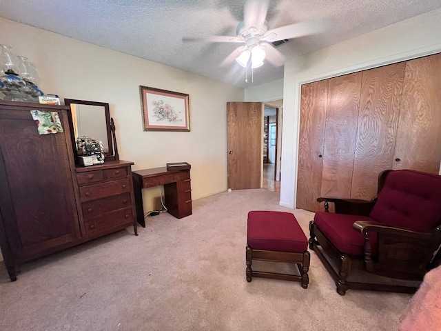 living area with a textured ceiling, light carpet, and ceiling fan