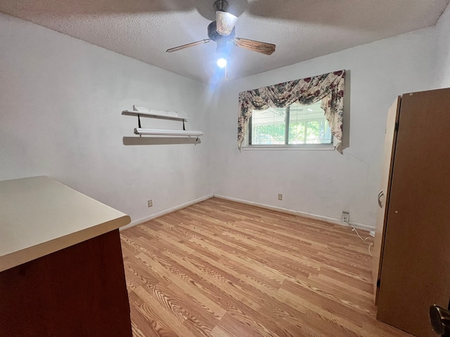 empty room with ceiling fan, a textured ceiling, and light hardwood / wood-style floors