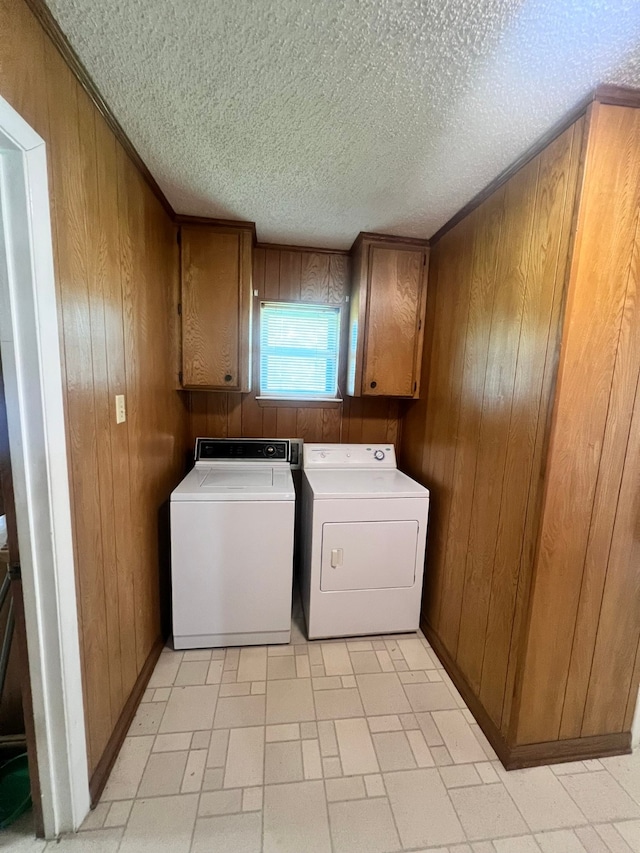 laundry room with cabinets, wood walls, a textured ceiling, and independent washer and dryer