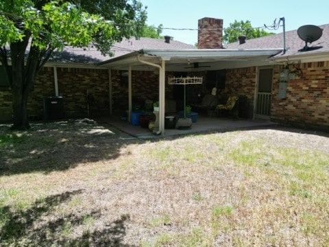 back of house with a lawn and a patio