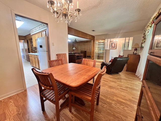 dining space featuring an inviting chandelier, a textured ceiling, and light wood-type flooring