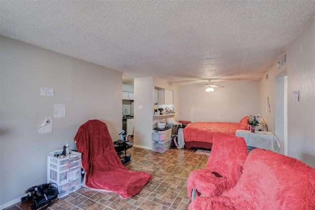 bedroom featuring ceiling fan, sink, and a textured ceiling