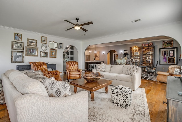 living room featuring light wood-type flooring, ceiling fan, and ornamental molding