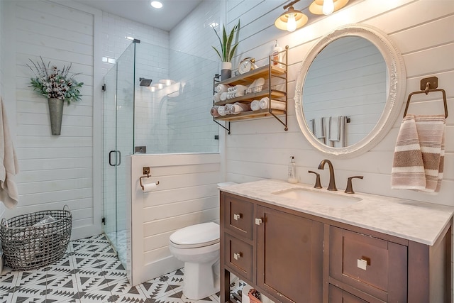 bathroom with vanity, tile patterned floors, wooden walls, toilet, and an enclosed shower