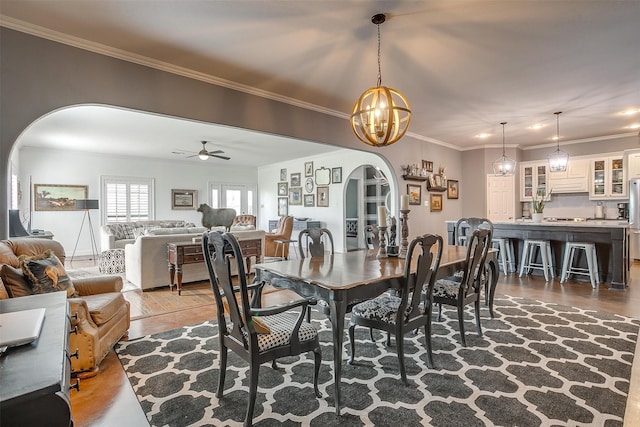 dining room featuring ceiling fan with notable chandelier, hardwood / wood-style flooring, and crown molding