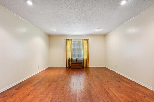 unfurnished room featuring hardwood / wood-style floors, ornamental molding, and a textured ceiling