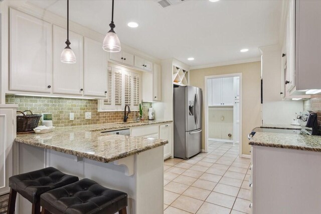 kitchen with stainless steel refrigerator with ice dispenser, hanging light fixtures, light stone countertops, tasteful backsplash, and kitchen peninsula