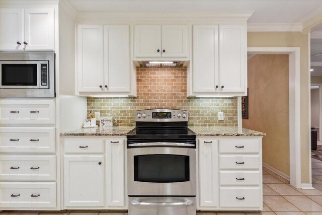 kitchen with light tile patterned floors, decorative backsplash, appliances with stainless steel finishes, light stone countertops, and white cabinets